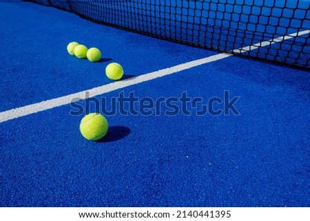 selective focus, five paddle tennis balls and the net of a blue paddle tennis court Royalty-Free Stock Photo #2140441395