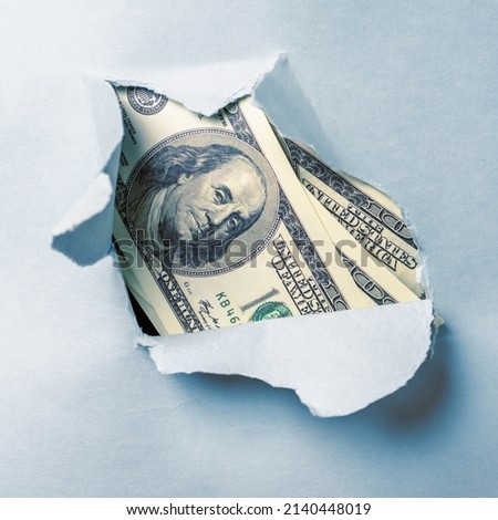 Hole ripped in textured paper background surface with one hundred US Dollar bills. Business, economic confrontation and crisis, sanction concept. 