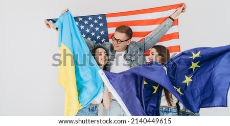 Happy friends holding flag Ukraine, USA and EU. 