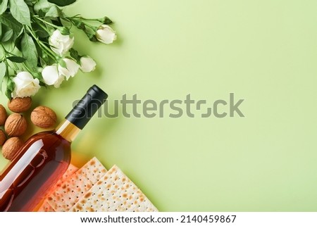 Passover celebration concept. Matzah, red kosher wine, walnut and spring beautiful rose flowers. Traditional ritual Jewish bread on light green background. Passover food. Pesach Jewish holiday. Royalty-Free Stock Photo #2140459867