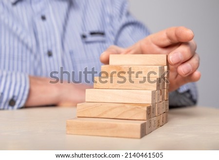 Businessman hand stacking wood blocks in career ladder. Professional development, growth, promotion, aims achievement. Aspiration. High quality photo