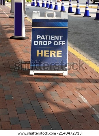 Sandwich board sign on a brick sidewalk near a driveway that says, Patient Drop Off Here