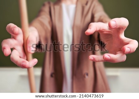 Woman teacher pulls her hands forward and wants to grab on school blackboard in the classroom Royalty-Free Stock Photo #2140473619