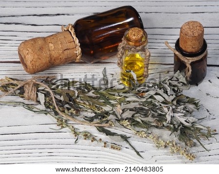 Dry leaves and flowers of wormwood herb, natural oil, drink tincture in a bottles on a white wooden background, flat layout. Medicinal plant artemisia for use in medicine,homeopathy and cosmetology Royalty-Free Stock Photo #2140483805