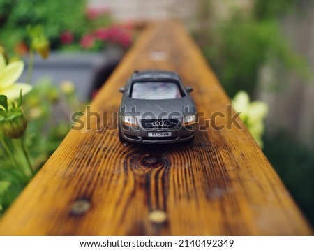 Macro shot of miniature Audi car model on garden decking fence, sorrounded by foliage Royalty-Free Stock Photo #2140492349
