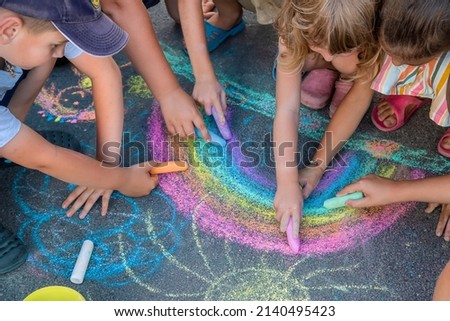 Children paint a rainbow on the asphalt. Selective focus. Kids. Royalty-Free Stock Photo #2140495423