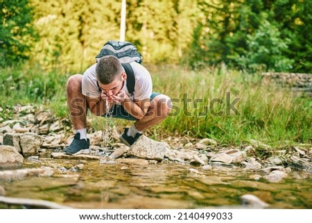 Man drinking fresh spring water while trekking. Selective focus. High-quality photo