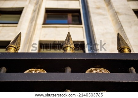 Pointed peaks on the fence, against the backdrop of the building.