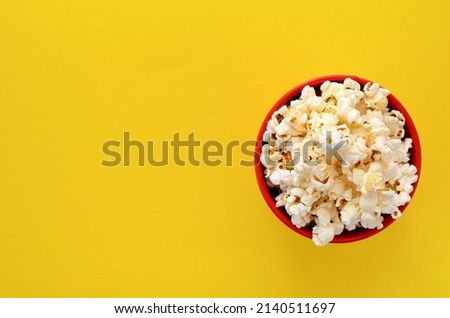 a bucket of popcorn on a yellow background flat lay, copy space