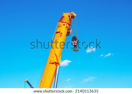 Heavy-duty truck crane boom. Raised arrow of a truck crane against the sky. Royalty-Free Stock Photo #2140513635
