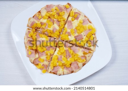 Traditional Hawaiian pizza, with cheese, pineapple, pomodoro pasta on checkered napkin