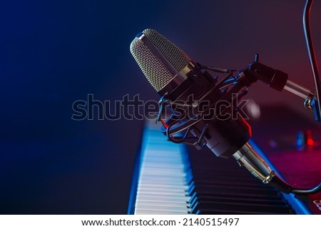 Musical instrument - midi keyboard and microphone on a blue background. Electronic equipment, recording studio, vocals, music, music video, music album recording. Banner, poster, invitation. Royalty-Free Stock Photo #2140515497