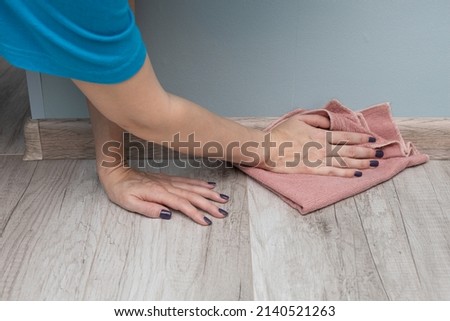 a woman during cleaning wipes the baseboard with a rag. High quality photo Royalty-Free Stock Photo #2140521263