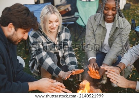 Young friends warming hands by fire at forest