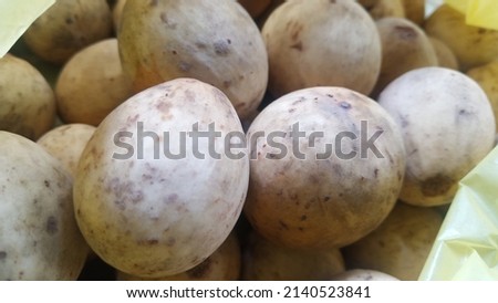grainy and blurry picture of a brown ball fruit called as Lansium domesticum or Lansium parasiticum langsat kokosan pisitan celoring tropical fruit that very small