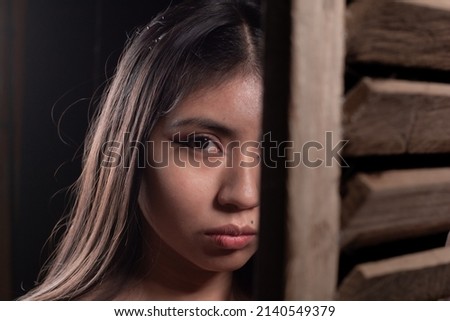face of latina girl behind wooden shutters, low key photography