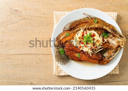 Fried Sea Bass Fish with Fish Sauce and Spicy Salad on plate Royalty-Free Stock Photo #2140560435