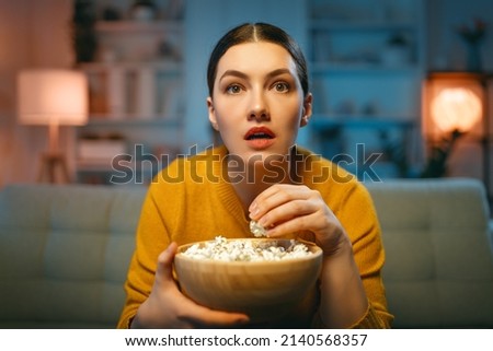 Young woman watching  TV, movies with popcorn. Girl spending time at home. Royalty-Free Stock Photo #2140568357