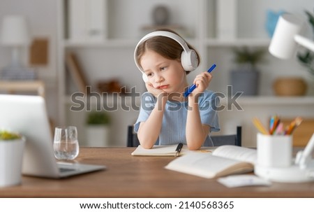 Back to school. Unhappy child is sitting at desk. Girl doing homework or online education. Royalty-Free Stock Photo #2140568365