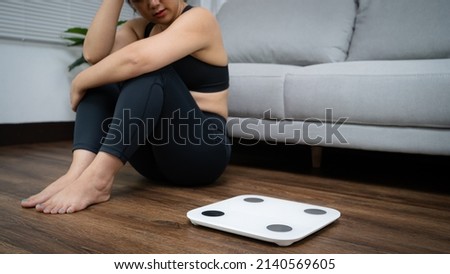 Asian healthy woman bored of dieting Weight loss fail  Fat diet and scale sad asian woman Upset on weight scale at home weight control. Royalty-Free Stock Photo #2140569605