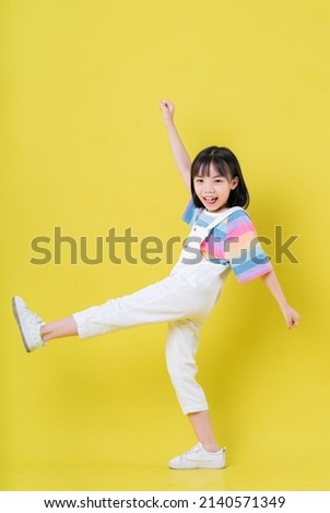 Full length image of Asian child posing on yellow background