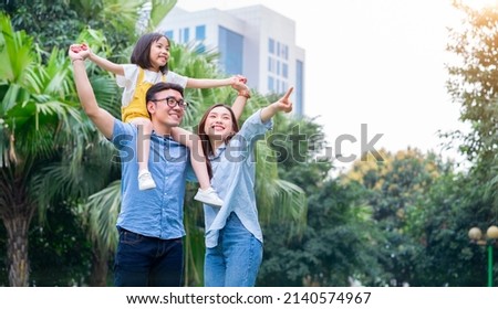 Image of young Asian family playing together at park