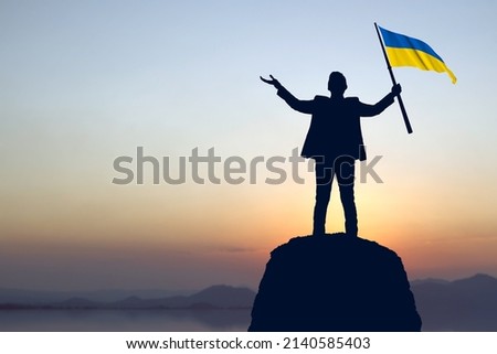 Silhouette of a businessman holding Ukraine flag with sunrise background