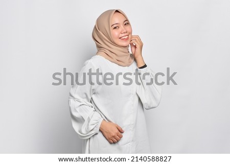 Smiling young Asian Muslim woman feels confident and joyful isolated over white background Royalty-Free Stock Photo #2140588827