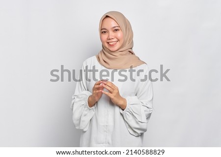 Smiling Asian Muslim woman holding hands together and feels joyful isolated over white background Royalty-Free Stock Photo #2140588829