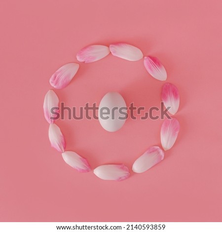 White easter egg in the centre of pink tulip petals ring. Wreath on pastel background. Flat lay minimal concept