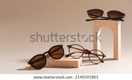 Trendy sunglasses of different design and eyeglasses on a beige background. Copy space. Sunglasses and spectacles sale concept. Optic shop promotion banner. Eyewear fashion. Minimalism Royalty-Free Stock Photo #2140595801