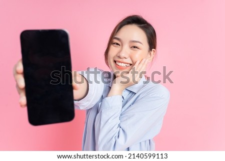 Image of young Asian girl holding smartphone on pink background Royalty-Free Stock Photo #2140599113