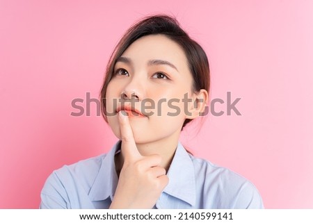 Portrait of young Asian girl posing on pink background