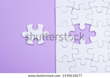 Puzzle pieces on orchid surface. White jigsaw game grid texture. Matching, inserting last missing part. Business and teamwork problem solving background. Copy space for add text, close up. Royalty-Free Stock Photo #2140618677