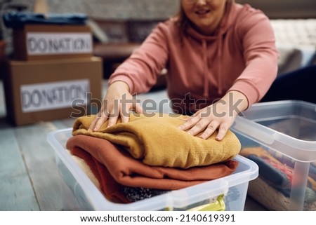 Close-up of woman packing donation box with clothes for people in need. Royalty-Free Stock Photo #2140619391