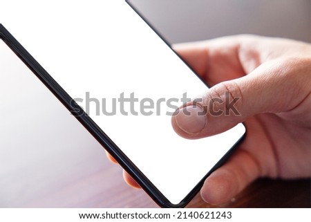 Close up photo of cell phone in man's hands, empty white screen mockup