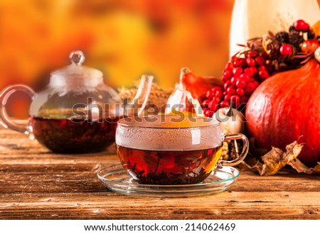 Cup of tea with autumn leaves with season vegetable on wooden table 