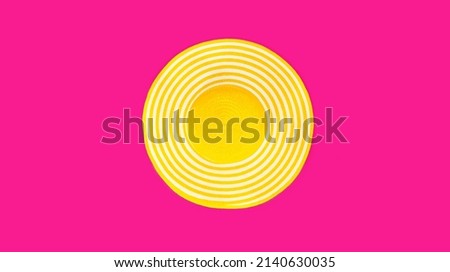 Summer yellow straw beach hat on colorful pink background, top view