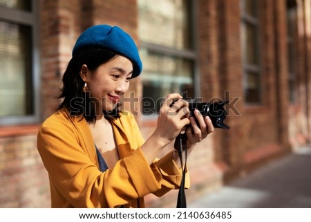 Beautiful Chinese woman with camera. Happy smiling woman taking photos of beautiful location.	