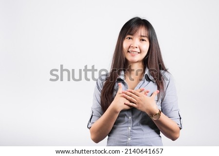 Happy woman in casual clothes holding hands at chest close to heart meditating and smiling in studio short isolated on white background, believe faith and love gratitude concept Royalty-Free Stock Photo #2140641657