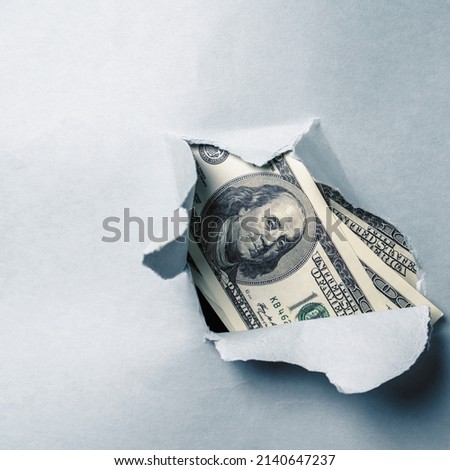 Hole ripped in textured paper background surface with one hundred US Dollar bills. Close uup. Business, economic confrontation and crisis, sanction concept. Copy space for design.