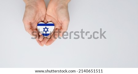 The national flag of Israel with the coat of arms in female hands. Flat lay, copy space. Royalty-Free Stock Photo #2140651511