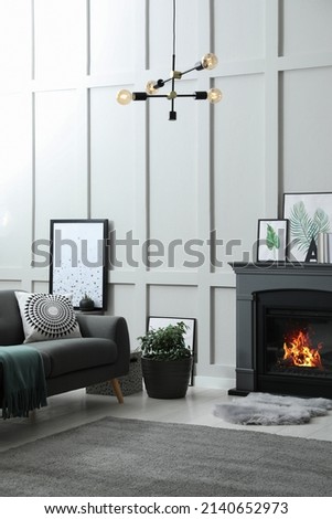Stylish living room interior with electric fireplace and comfortable sofa