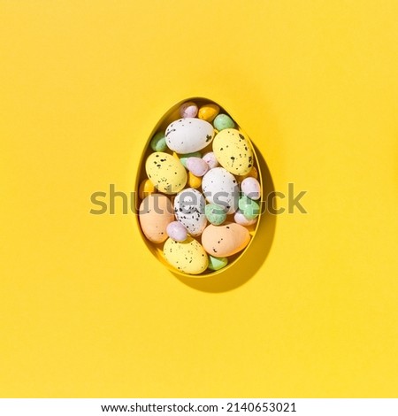 Festive holiday Easter composition. Yellow, pink, blue and white easter eggs on paper yellow background. Spring Easter card concept. Flat lay, top view, copy space. Royalty-Free Stock Photo #2140653021