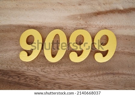 Wooden  numerals 9099 painted in gold on a dark brown and white patterned plank background.
