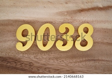 Wooden  numerals 9038 painted in gold on a dark brown and white patterned plank background.