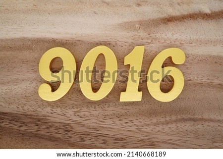 Wooden  numerals 9016 painted in gold on a dark brown and white patterned plank background.