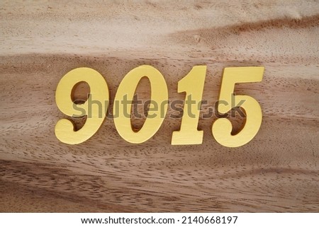 Wooden  numerals 9015 painted in gold on a dark brown and white patterned plank background.