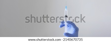 Close-up of person hand holding syringe with transparent substance. Injection
