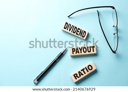Text DIVIDEND PAYOUT RATIO concept on the wooden block on blue background